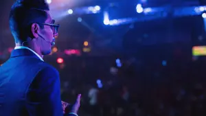 David on stage facing a crowd under stage lights