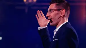 David speaking with a headset microphone under blue light
