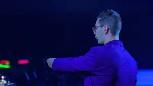 David on stage gesturing under purple light