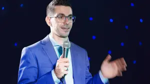 David speaking into a microphone in a blue suit