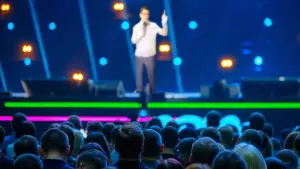 Speaker on a large lit stage in front of a big audience